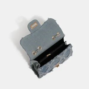 Denim chain shoulder bag detail showing interior compartment and gold hardware clasp.