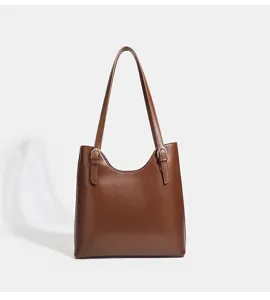 Détail de sac cabas épaule en cuir marron avec design seau élégant et boucle en métal.