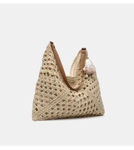 Gewebte Stroh-Shopper-Tasche Detail mit braunen Lederriemen und süßem Plüschanhänger.