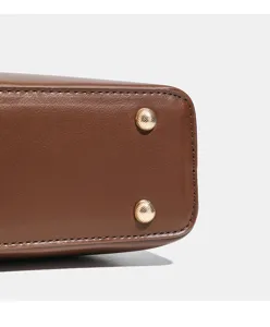 Gros plan sur le fond du sac cabas femme en cuir marron avec des pieds en metal.