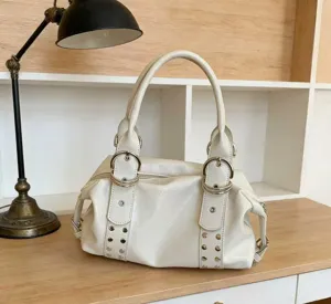 Nahaufnahme der weißen Handtasche aus weichem Leder mit metallischen Schnallen und Nieten.