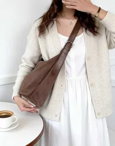 Detailansicht der braunen Wildleder-Hobo-Schultertasche, getragen vom Model, Herbststil.