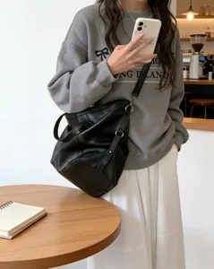 Detalle de bolso saco de cuero suave negro, gran bolso cruzado informal para mujer.