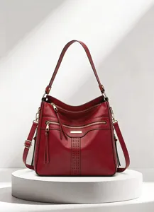 Detailansicht der eleganten roten Ledertasche mit mehreren Reißverschlüssen und Quasten.