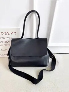 Nahaufnahme einer klassischen schwarzen Umhängetasche mit Klappe und breitem Gurt.