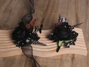 Détail de boutonnière et fleur de poignet de mariage de rose noire artificielle, style gothique.