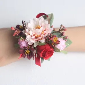 Detailansicht einer Hochzeits-Handgelenkblume mit künstlichen rosa Gänseblümchen und roten Rosen.