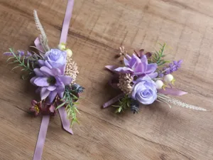 Détail de corsage de poignet de fleurs artificielles violettes et boutonnière pour mariage.