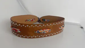 Wide brown leather belt featuring metal studs and colorful woven scarf details for women.