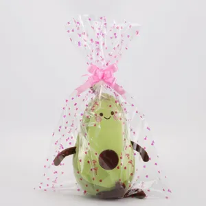 Adorably soft avocado plush toy packed in clear printed gift bag with a pink bow.