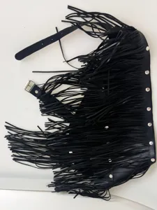 Close-up detail of black leather fringe waist belt with metal rivets and buckle design.