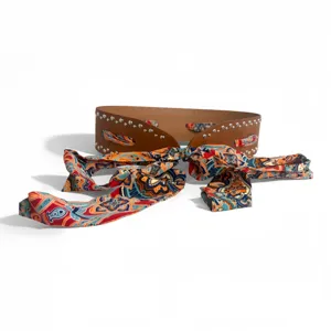 Wide brown leather belt with metallic studs and colorful paisley silk scarf bow design.