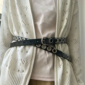 Dubbele zwarte PU lederen riem met metalen oogjes gedragen in de taille als modieus accessoire.