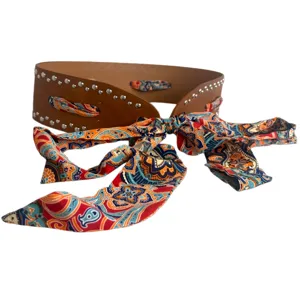 Wide brown leather belt with metal studs and colorful paisley scarf bow for women fashion.