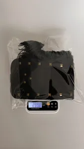 Detail view of black punk rivet fringe belt, showing weight on digital scale for quality check.