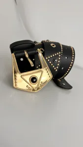 Close-up of a punk style black leather belt with ornate gold buckle and rivet studs.