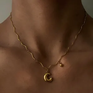 Detailaufnahme einer 18k vergoldeten Edelstahl Wellenkette mit fluffigem Buchstaben C Anhänger.
