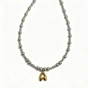 Stainless steel round bead necklace gold bubble letter jewelry close up detail view.