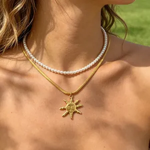 Stunning double layer necklace set featuring a white pearl choker and a chic gold sun face pendant.
