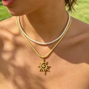 Detailed close-up of a double-layered necklace featuring a pearl choker and a gold sun pendant.