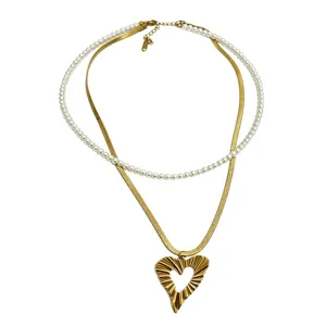Trendy double layer pearl and gold snake chain necklace with hollow textured heart pendant.