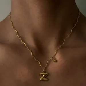 Nahaufnahme einer goldenen Wellenkette mit einem puffy Buchstaben Z Anhänger am Hals.