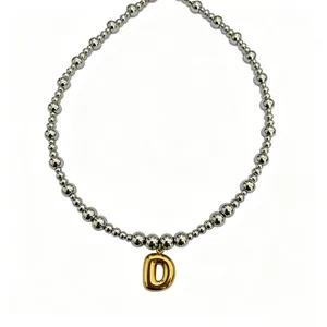Close-up detail of silver-tone beaded necklace featuring a stylish gold bubble letter D pendant.