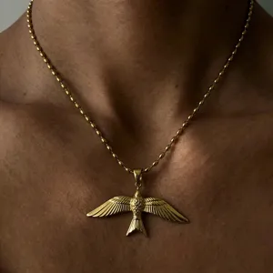 Gros plan élégant du collier pendentif oiseau doré montrant des détails de plumes fins.