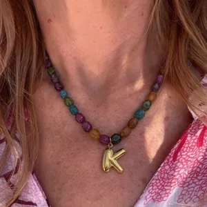 Detailed shot of colorful beaded necklace featuring a stylish gold initial letter K pendant.