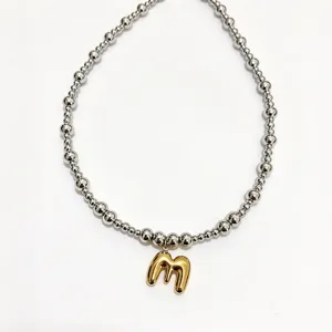 Detailed close-up view of the stainless steel beaded necklace with a golden letter pendant.