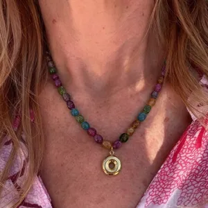 Colorful beaded necklace with gold donut pendant close-up, stylish jewelry detail shot.