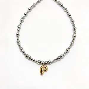 Close-up detail of stainless steel beaded choker necklace featuring gold bubble letter P.