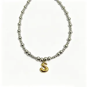 Stainless steel beaded chain necklace featuring a shiny gold bubble letter S pendant detail.