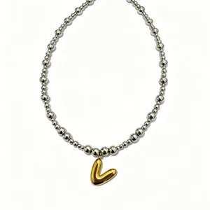 Stainless steel beaded necklace with gold puffy letter pendant, fashion clavicle jewelry detail.