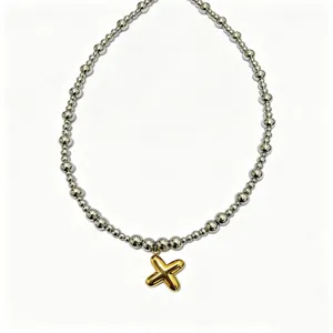 Close-up detail of the trendy stainless steel bead chain with a gold puffy letter pendant.