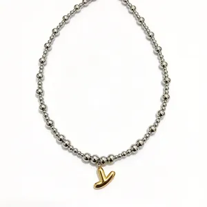 Detail shot of stainless steel bead necklace with gold bubble letter pendant, chic clavicle chain.