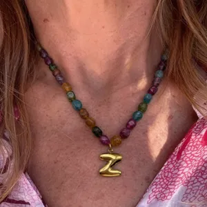 Detail shot of colorful gemstone bead necklace featuring a shiny gold letter Z pendant.