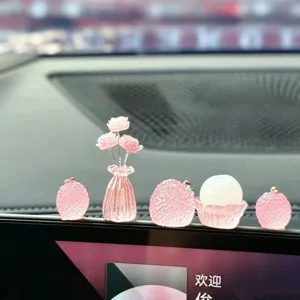 Car ornament detail showing cute pink resin rose vase and glowing lychee dashboard decor.