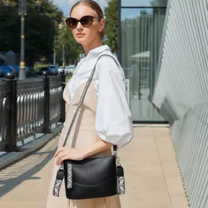 Close-up of a stylish black bucket shoulder bag with patterned straps worn by a model outdoor.
