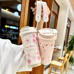 Detail view of portable stainless steel travel coffee mug with cherry blossom design and strap.
