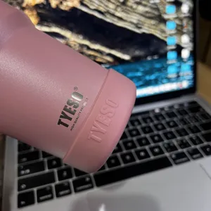 Roze roestvrijstalen geïsoleerde beker met siliconen beschermboot. Detailweergave logo.