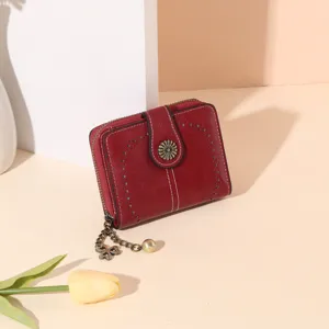 Detailed close-up of a vintage red short women wallet featuring floral snap buckle and cute clover charm.