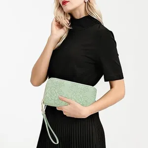 Elegant light green embossed long wallet for women with zipper and wrist strap detail.