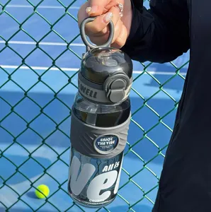 Detail shot of a large-capacity sports water bottle with straw and portable handle outdoors.