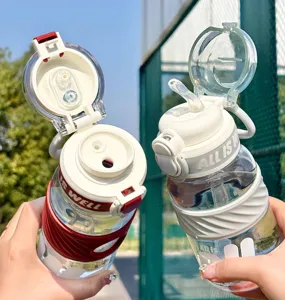 Close-up of dual-drink sports water bottles held outdoors, showing straw lids and silicone grips.