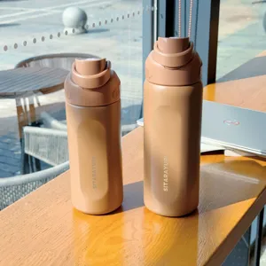 Detailed shot of two portable brown water bottles placed neatly on wooden table near window.