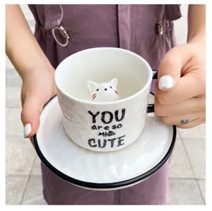 Close-up of ceramic coffee cup featuring adorable 3D cat inside with cute English text design.