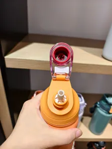 Gros plan sur le couvercle de la bouteille d'eau orange et la paille, joint anti-fuite visible.