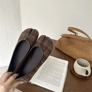 Vista dettagliata di scarpe basse marroni a quadri con punta divisa, stile Tabi unico.