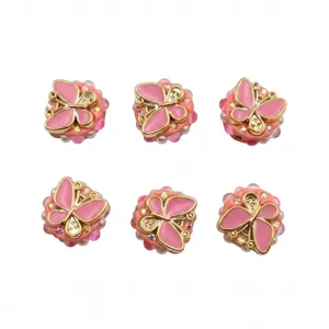 Vista detallada de cuentas de resina de mariposa rosa con detalles dorados para manualidades.